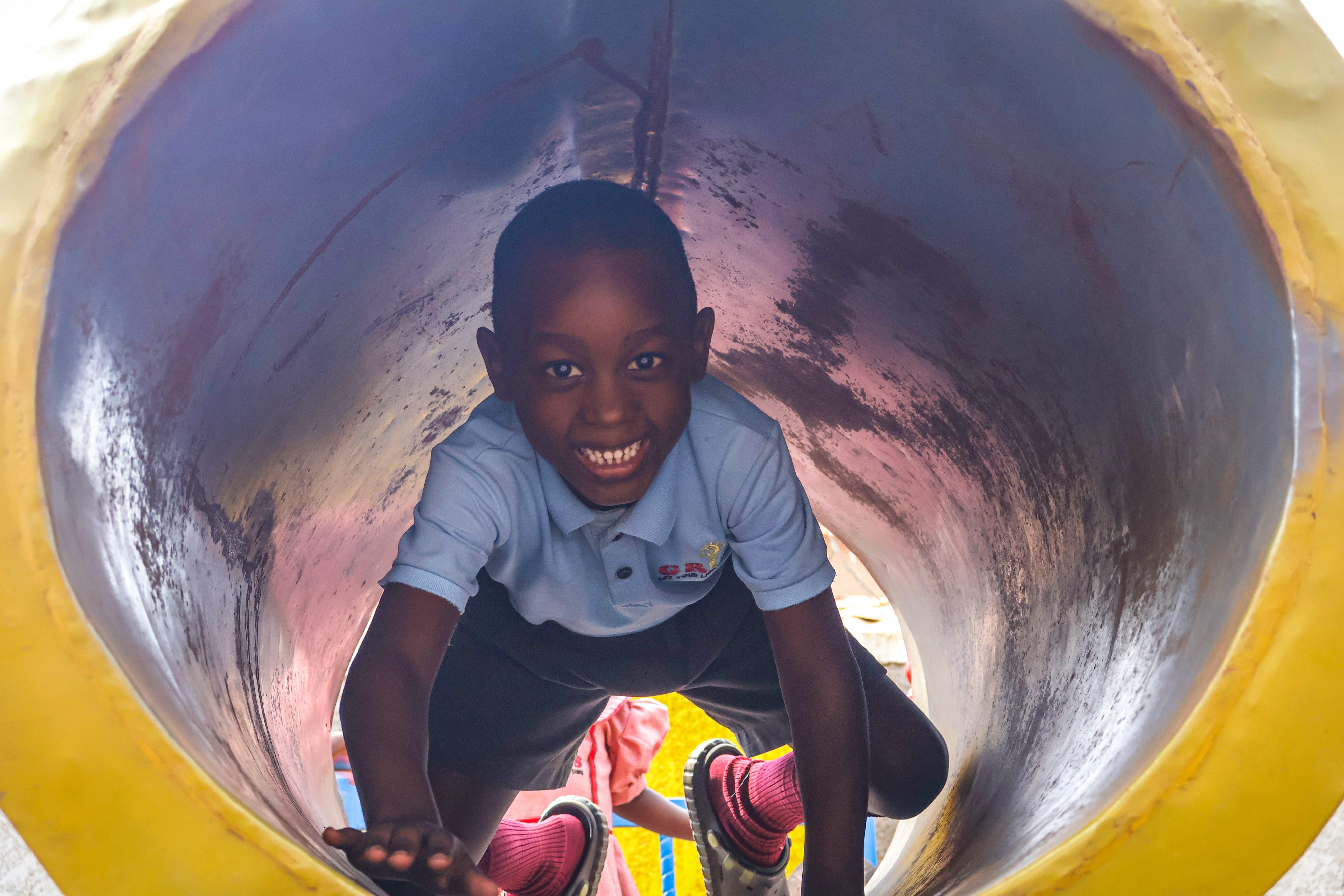 Student smiling inside the tunnel slide on the playground